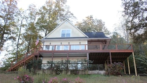 Een huis met twee verdiepingen, een balkon, een trap en een tuin met roze bloemen.