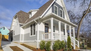 A two-story house with a front porch, a steeply pitched roof, and a visible chimney.