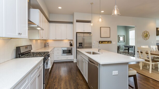 A modern kitchen with white cabinets, stainless steel appliances, and a central island with a sink.