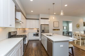 Una cocina moderna con armarios blancos, electrodomésticos de acero inoxidable y una isla central con pileta.