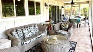 A covered patio area with wicker furniture, a round table, and a ceiling fan. - Garden Home at Botanical World Adventures 
Two Bedroom Three bathroom  (Hakalau)
