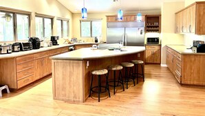 A modern kitchen with wooden cabinets, a large island with stools, and a built-in refrigerator. - Garden Home at Botanical World Adventures 
Two Bedroom Three bathroom  (Hakalau)