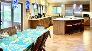 A spacious kitchen with wooden cabinets, a central island with stools, and pendant lights. - Garden Home at Botanical World Adventures 
Two Bedroom Three bathroom  (Hakalau)