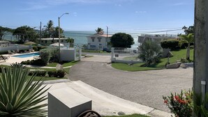 Un área residencial con piscina, un edificio blanco y vistas al mar.