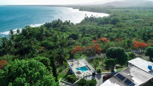 A residential area with a swimming pool, solar panels, and a view of the ocean.