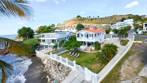 A coastal property with a white building, a stone retaining wall, and a view of the ocean.