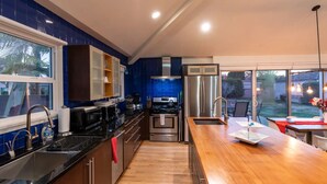 A modern kitchen with stainless steel appliances, a wooden countertop, and a view of the backyard.