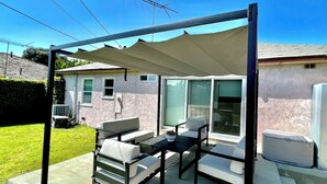 A covered patio area with outdoor furniture, a sliding glass door, and a white utility box.