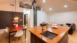 A modern kitchen with a central island, a dining area, and a laundry room.