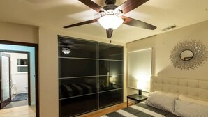 A bedroom with a bed, a ceiling fan, a wardrobe, and a mirror on the wall.