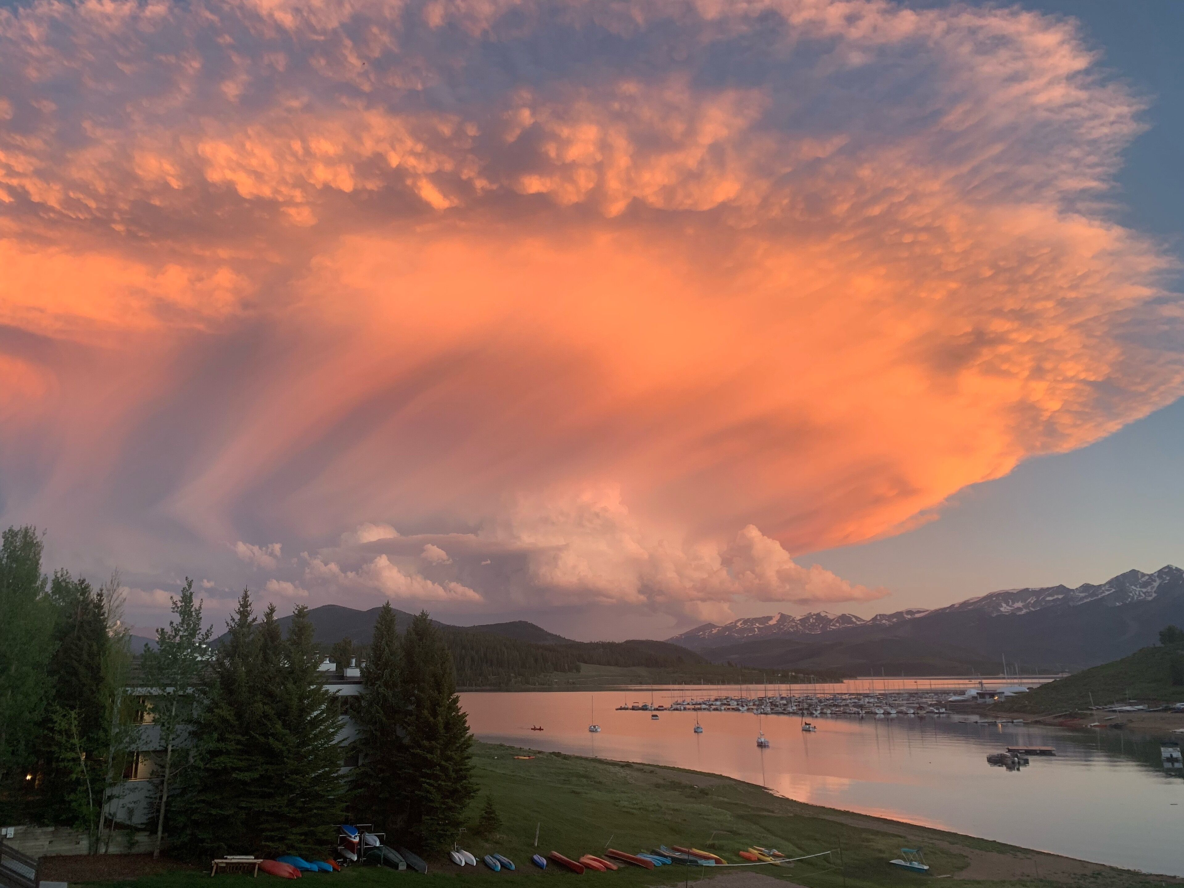 Une vue sur le lac, avec des bateaux, des montagnes et un coucher de soleil.