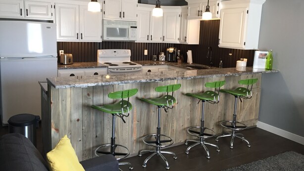 A modern kitchen with white cabinets, a central island with bar stools, stainless steel appliances, and pendant lighting. - Completely Remodeled 1 Bedroom -Extra-Large In Las Palmas (Saint George)