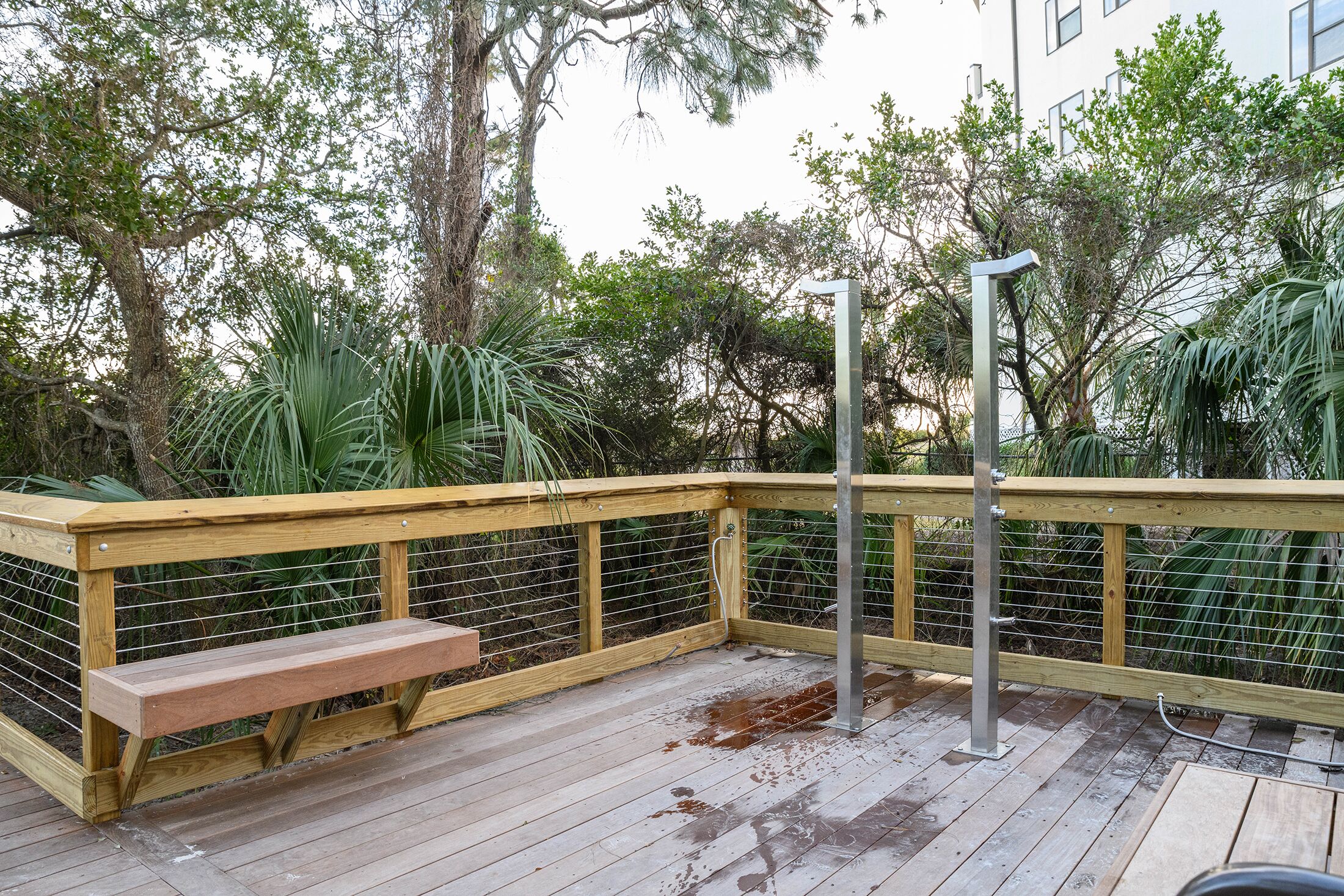 A wooden deck with a bench, metal railings, and a water feature.