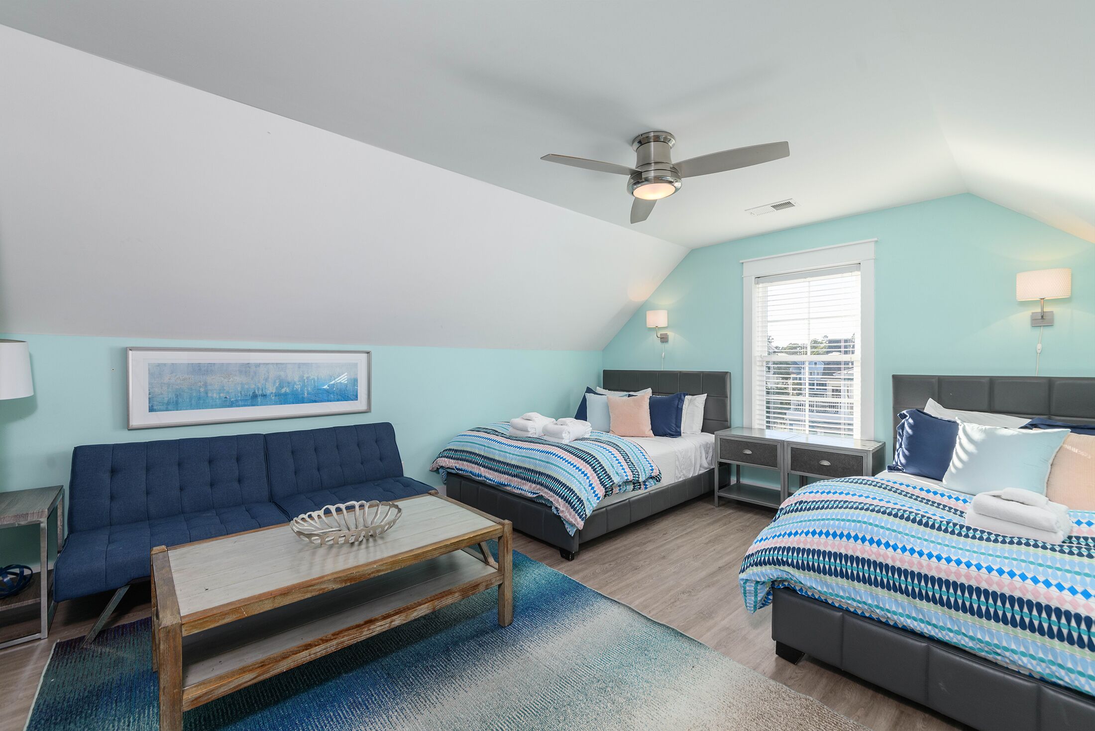 Un dormitorio con cama, sofá, mesa y ventilador de techo.