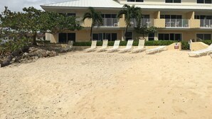 Um hotel à beira-mar com telhado plano, várias varandas e espreguiçadeiras.