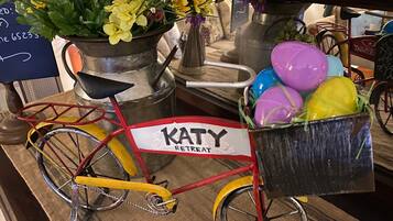 A bicycle with a basket labeled "KATY RETREAT" and a pot of flowers.