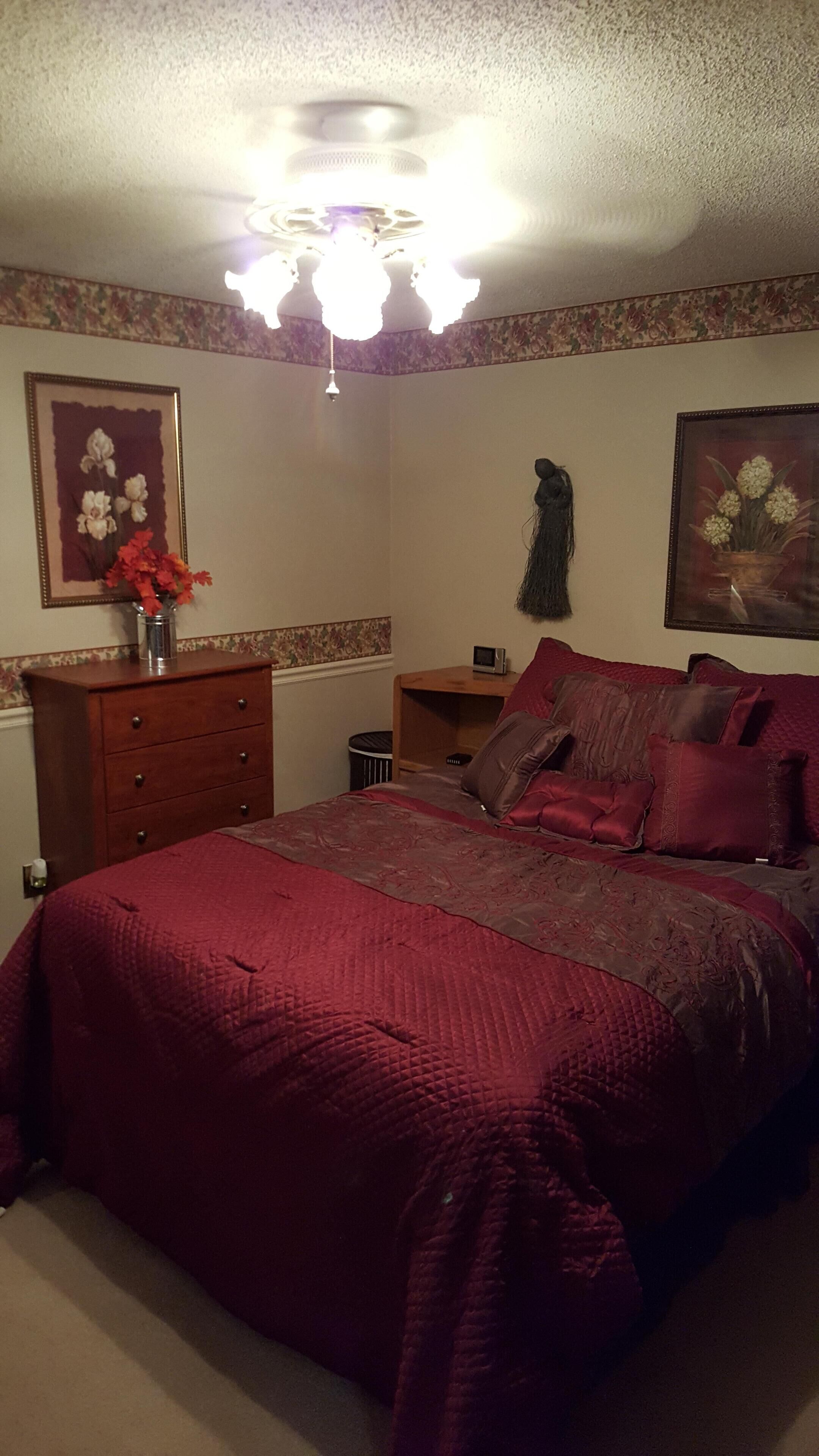 Un dormitorio con una cama grande, un aparador, una mesita de noche y un ventilador de techo.