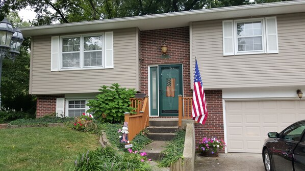 A two-story house with a green door, a brick facade, and a garage.