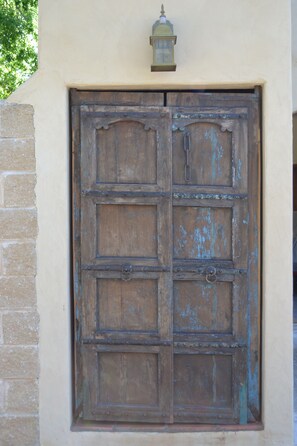 A large wooden door with a metal handle and a small lantern above it.