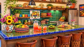 Une cuisine avec un mur recouvert de carreaux colorés, des tabourets de bar en bois et divers ustensiles de cuisine.