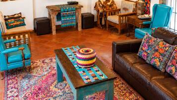 Un salon chaleureux avec un téléviseur, des meubles en bois, un tapis coloré et divers objets de décoration.
