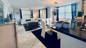 A modern kitchen with a dining area, white furniture, and a 'WELCOME' sign. - THE NAUTICAL!  FULLY EQUIPPED  3 BD 2BA APT AT AVENTURA  YACHT CLUB! (Aventura)