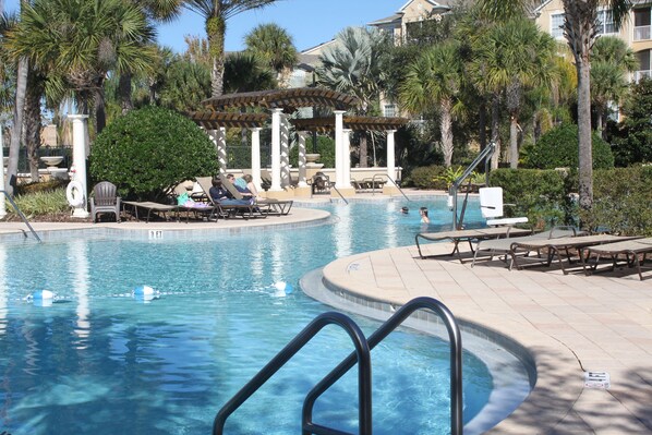 A swimming pool with lounge chairs and palm trees.