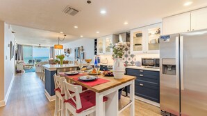 A modern kitchen with a central island, stainless steel appliances, and a view to the dining area. - WAKE UP TO THIS AMAZING VIEW - Large Balcony - New Kitchen & Bathroom (Indian Rocks Beach)