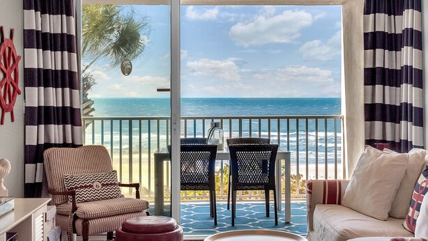 A room with a view of the ocean, a balcony with chairs, and a sofa. - WAKE UP TO THIS AMAZING VIEW - Large Balcony - New Kitchen & Bathroom (Indian Rocks Beach)