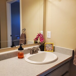 A bathroom with a white sink, a mirror, a towel rack, a potted plant, and a motivational sign. - Luxury in the Red Rocks: 4BD/2 BA, fenced backyard, Hot Tub (Moab)