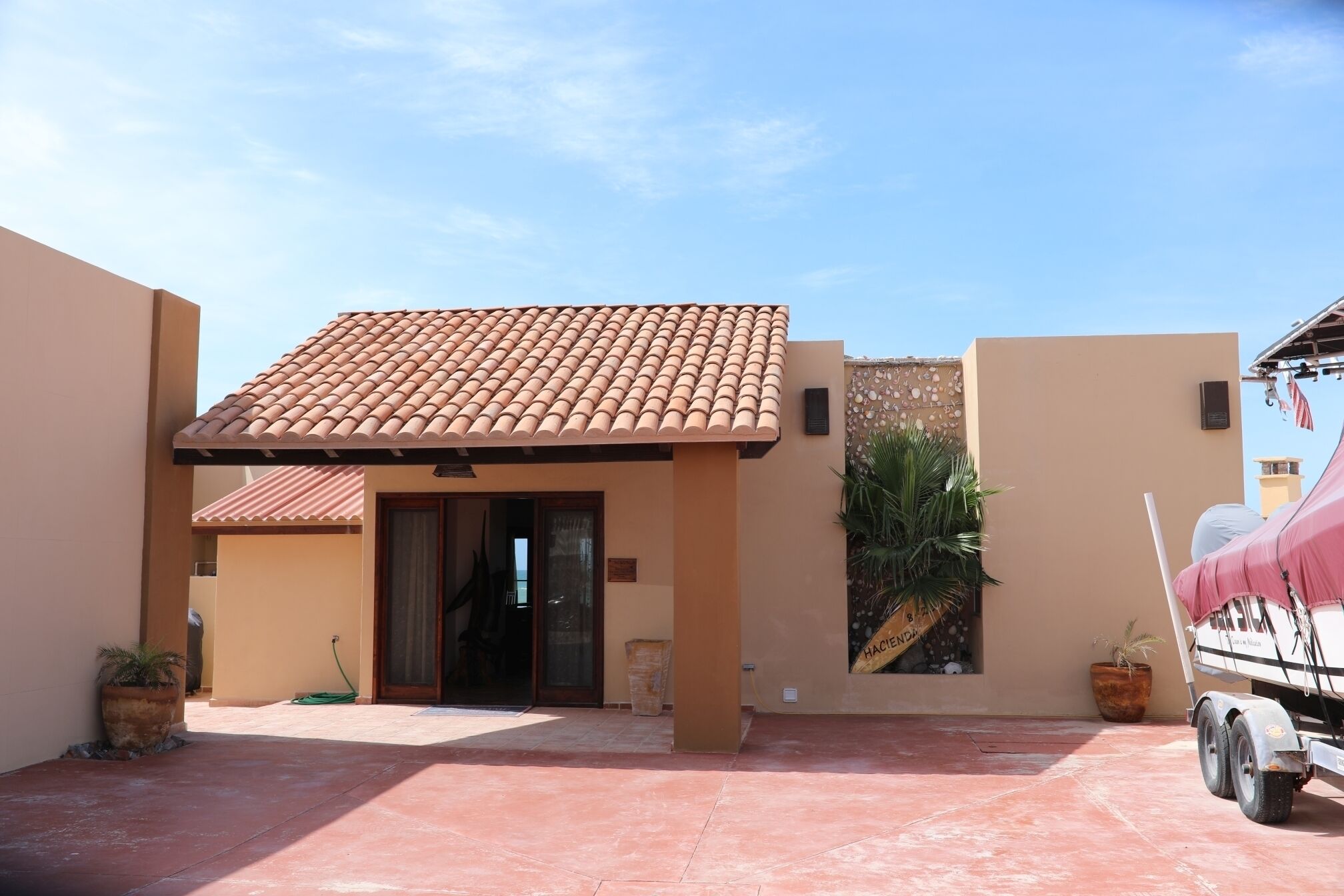 A building with a tiled roof, a covered entrance, and a paved courtyard.