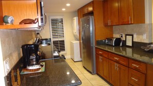 Una cocina con armarios de madera, un refrigerador de acero inoxidable, una cafetera y un tostador.