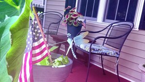 Varanda com planta em vaso, bandeiras americanas e uma cadeira de metal.