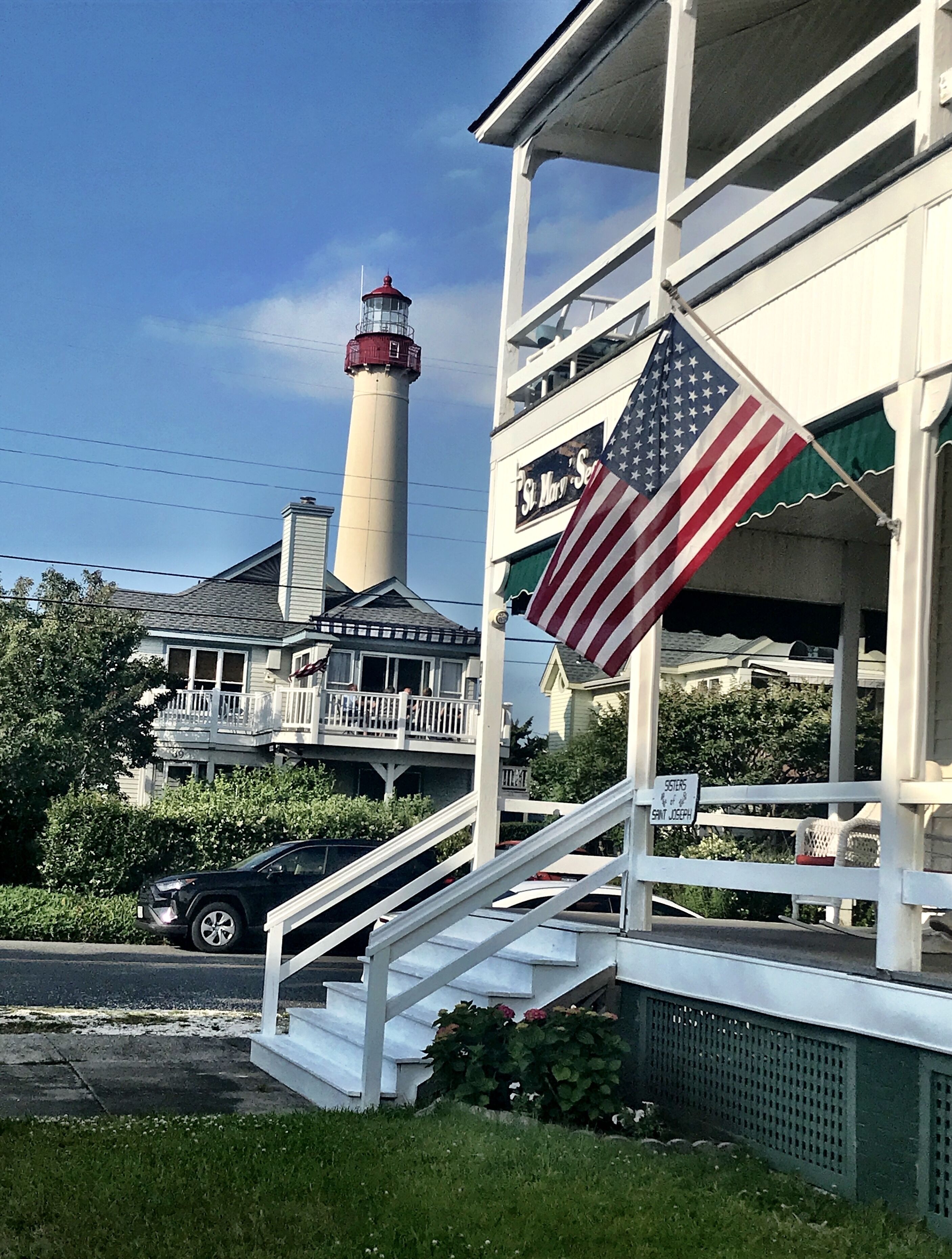 Un edificio con una escalera, una bandera estadounidense y un faro al fondo.