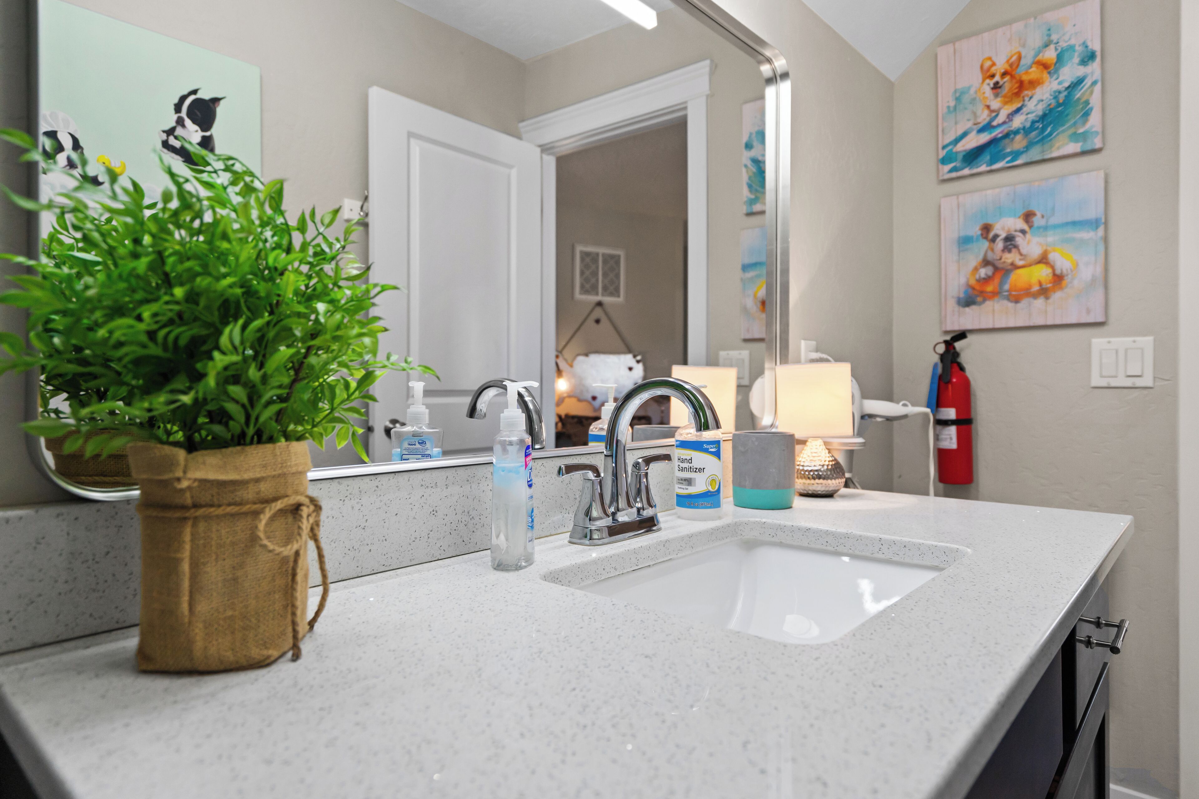 Un baño con lavamanos, espejo y una planta en maceta.