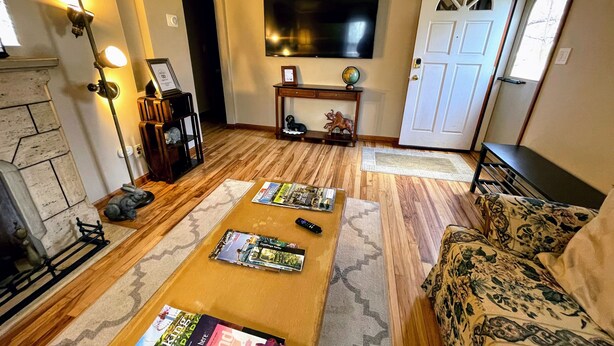 A living room with a fireplace, a TV mounted on the wall, and a door with a decorative glass panel. - CLE Garden Retreat, 4-Min to Airport & Metroparks, Ping Pong, BBQ & Private Yard (Cleveland)