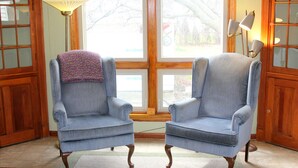 A room with two armchairs, a wooden floor, a window with a view, and a lamp. - CLE Garden Retreat, 4-Min to Airport & Metroparks, Ping Pong, BBQ & Private Yard (Cleveland)