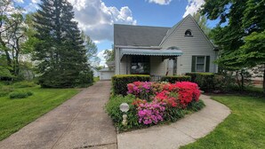 A residential house with a front yard, a driveway, and a well-maintained lawn. - CLE Garden Retreat, 4-Min to Airport & Metroparks, Ping Pong, BBQ & Private Yard (Cleveland)