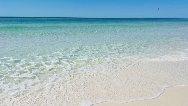 Ein Strand mit klarem türkisblauem Wasser und weißem Sand.