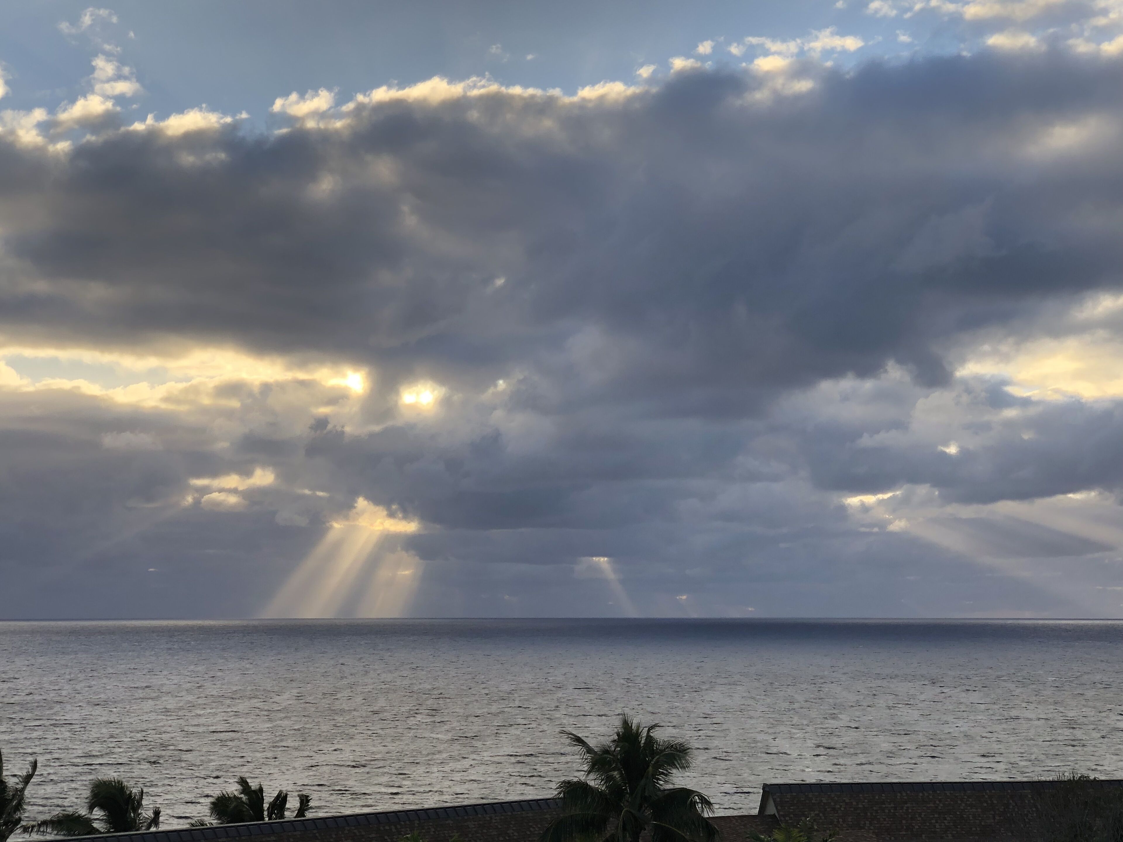 Vista costera con cielo nublado y rayos de sol.