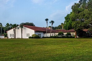 A white building with a red roof, surrounded by a grassy field and palm trees. - ♥️ SPECIAL-169 a night ! Pet Friendly ♥️ (Saint Augustine)