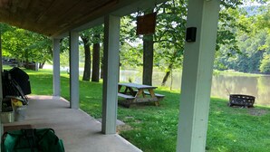 Un área de picnic techada con sendero de concreto, mesa y parrilla.