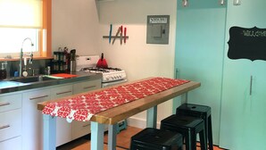 Una cocina con una mesa de madera, taburetes negros, un fregadero y una estufa.