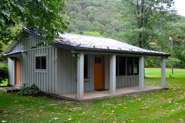 A small, single-story building with a porch, a door, and windows. - Cozy and relaxing, Modern Creekside, Trailside, Waterfront Cottage, fiber Wifi (Cammal)