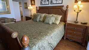 Ein Schlafzimmer mit einem großen Bett, einem Holz-Kopfteil und einem Nachttisch mit einer Lampe.