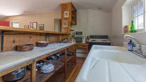 Cozinha com prateleiras de madeira, pia e janela.