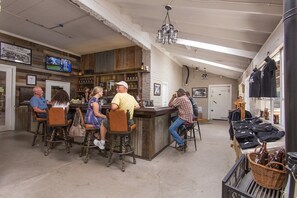 Un espace bar avec des tabourets de bar en bois, un comptoir et un téléviseur fixé au mur.