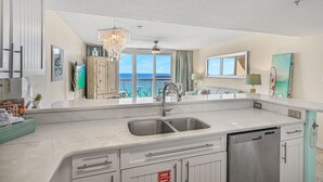 Una cocina moderna con una isla grande, electrodomésticos de acero inoxidable y vistas al océano.
