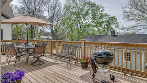 Une terrasse en bois avec une table et des chaises, un barbecue et une plante en pot.