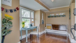 Une pièce avec un plancher en bois, un bureau avec une chaise, un banc et une guitare accrochée au mur.